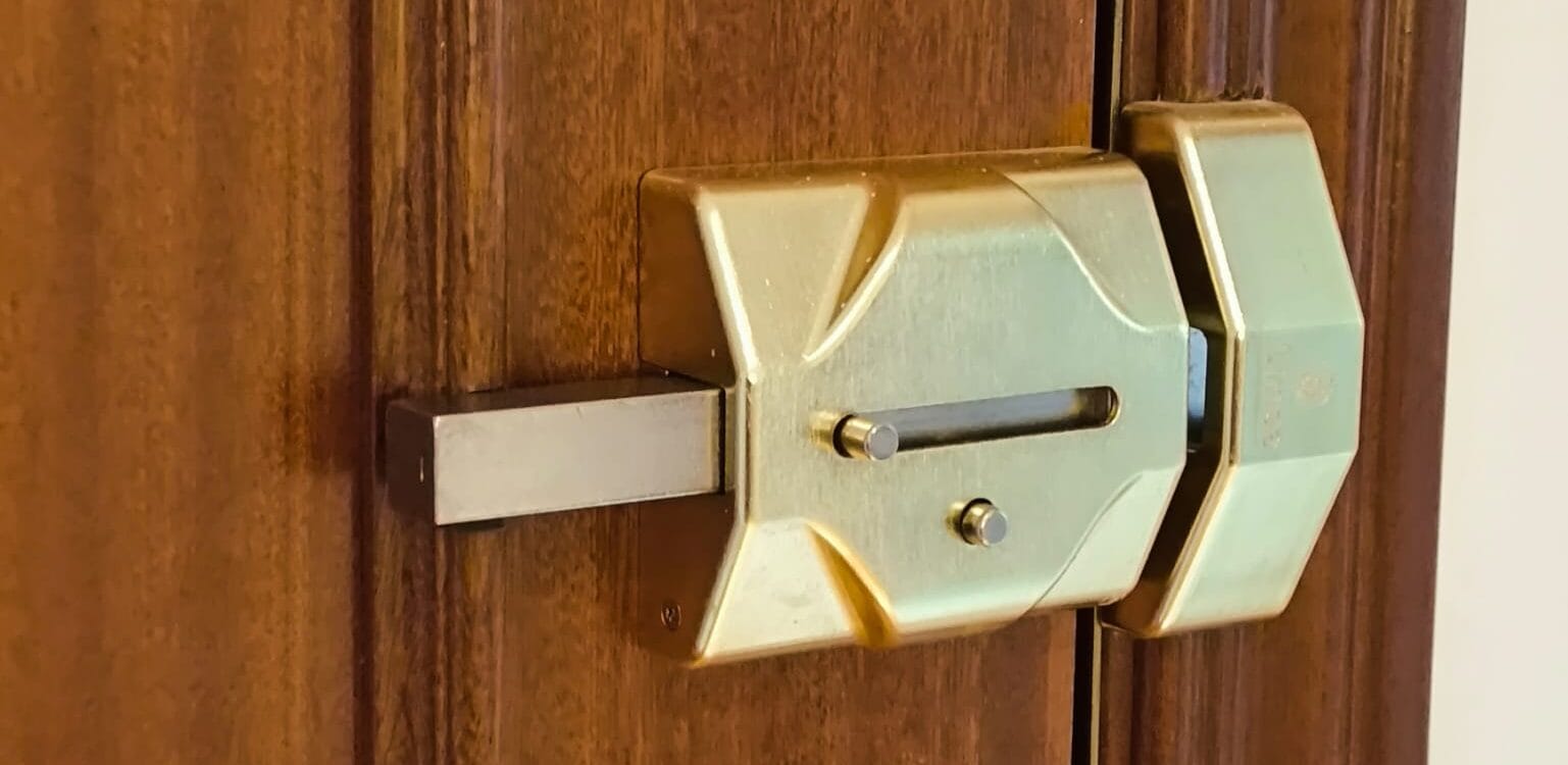 Cerrajero instalando un cerrojo de seguridad tipo FAC en una puerta de madera en Badajoz